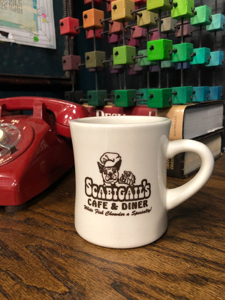 A retro Scabigail's Cafe & Diner mug sits on Alton Brown's desk on the set of Good Eats.